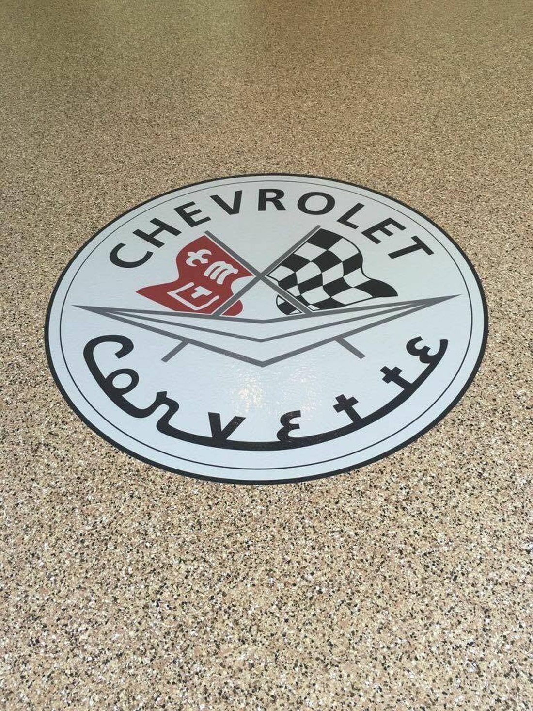 Custom Corvette logo inlay on flake epoxy garage floor